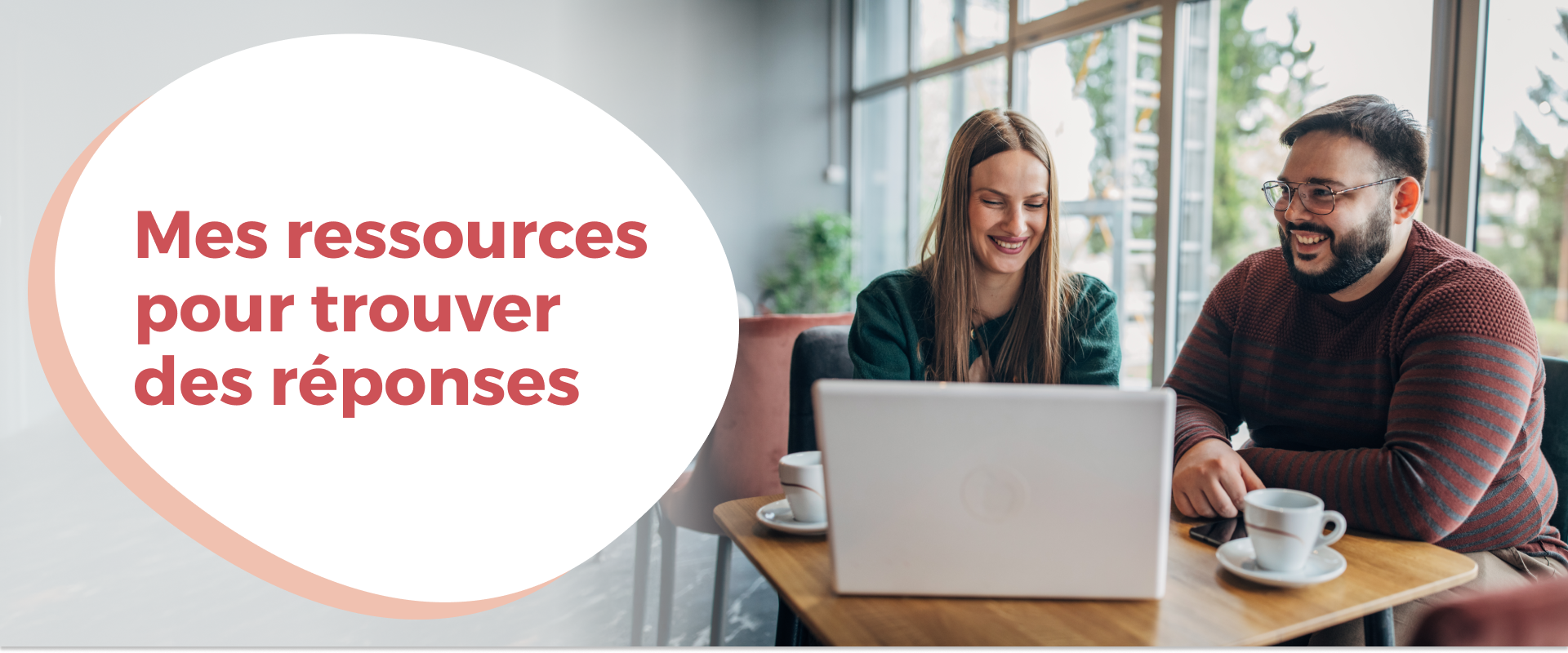 Une femme et un homme assis dans un café devant un ordinateur