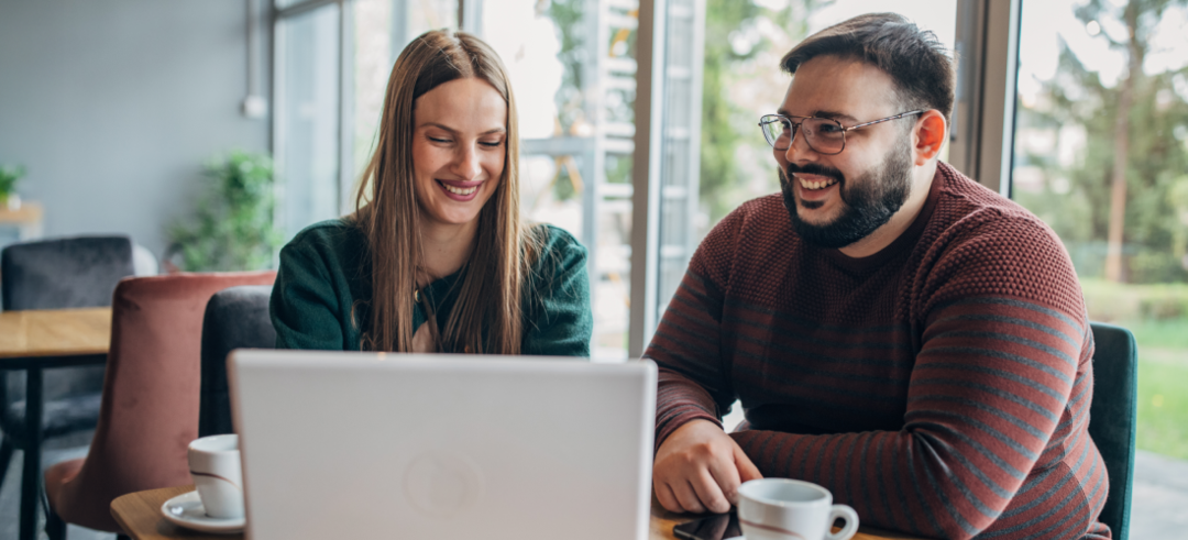 Un homme et une femme assis dans un café devant un ordinateur