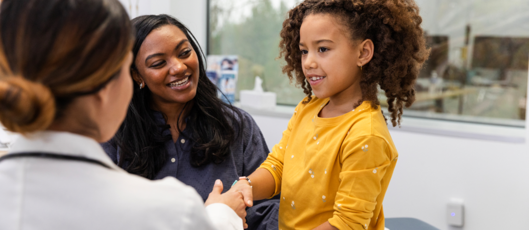 Petite fille serrant la main d'un docteur dans un cabinet avec sa maman