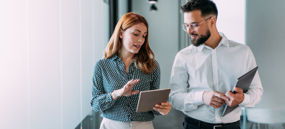 Femme et homme discutant en marchant tout les 2 une tablette en main
