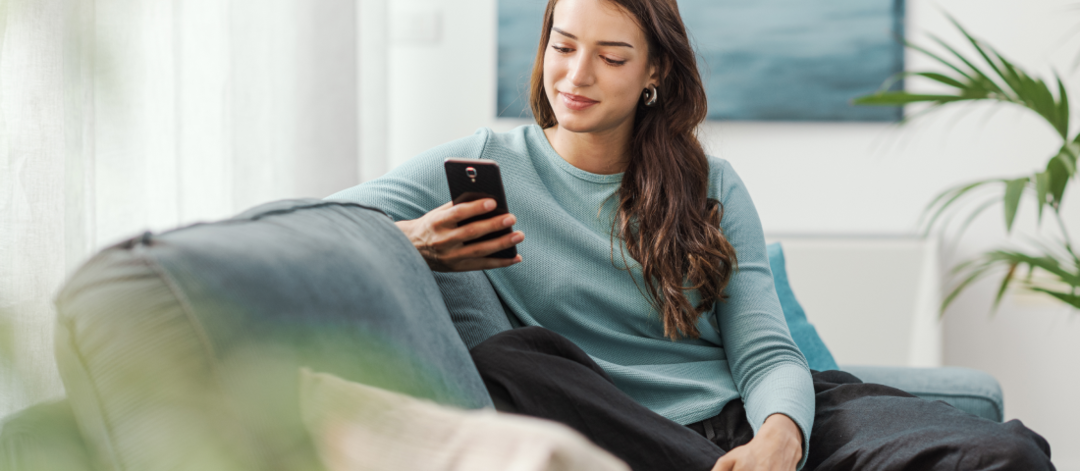 Femme assise sur un canapé et scrollant sur son téléphone portable