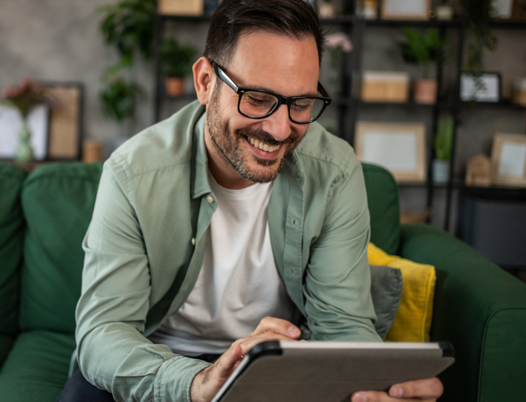 Homme souriant devant sa tablette